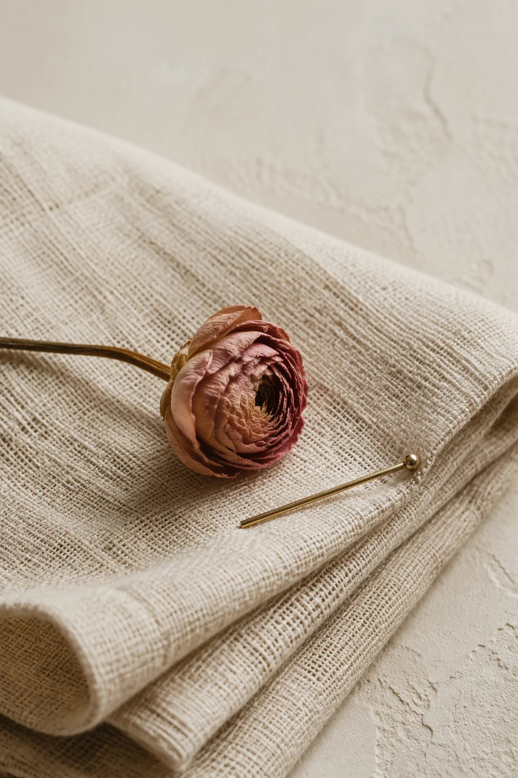 Folded natural linen with a dried ranunculus flower